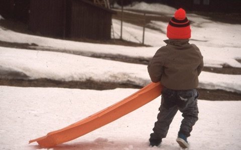 1990s unknown kid sledding near lodge