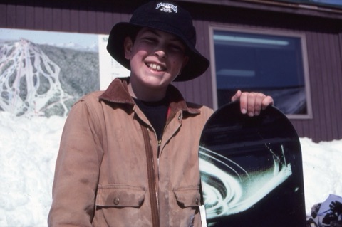 1990s unknown kid with snowboard on lodge deck