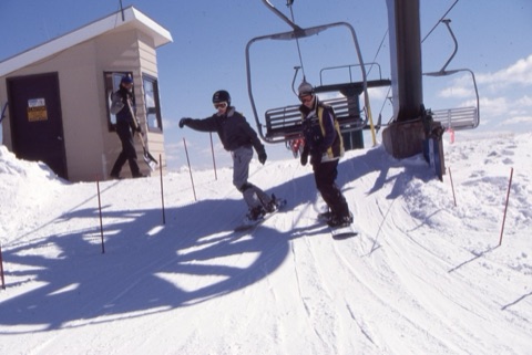 2000s unknown snowboarders unloading from triple chair