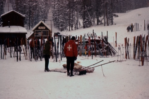 1960's Ski Patrollers with Toboggans, lots of Skis with the Ski Hut in the background