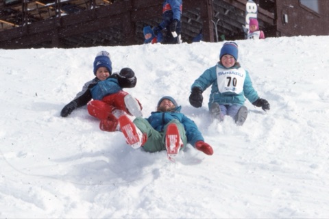 1989 Kids sliding down on snow near lodge - Frank Ball Photo 40