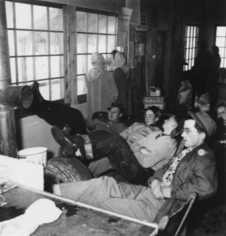 1940s Young men around a drum stove inside a hut