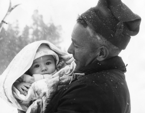 1950s-60s A man in a knit cap with a baby in the snow